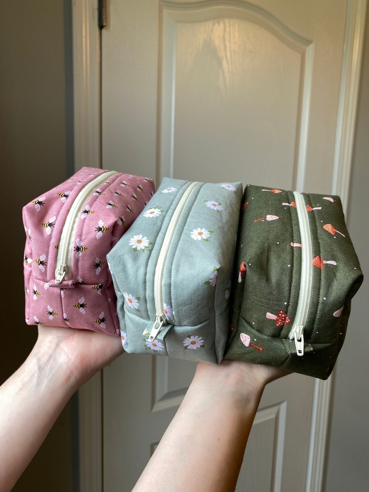 Three finished boxy zip pouches in bee, daisy and mushroom prints, made by the reviewer