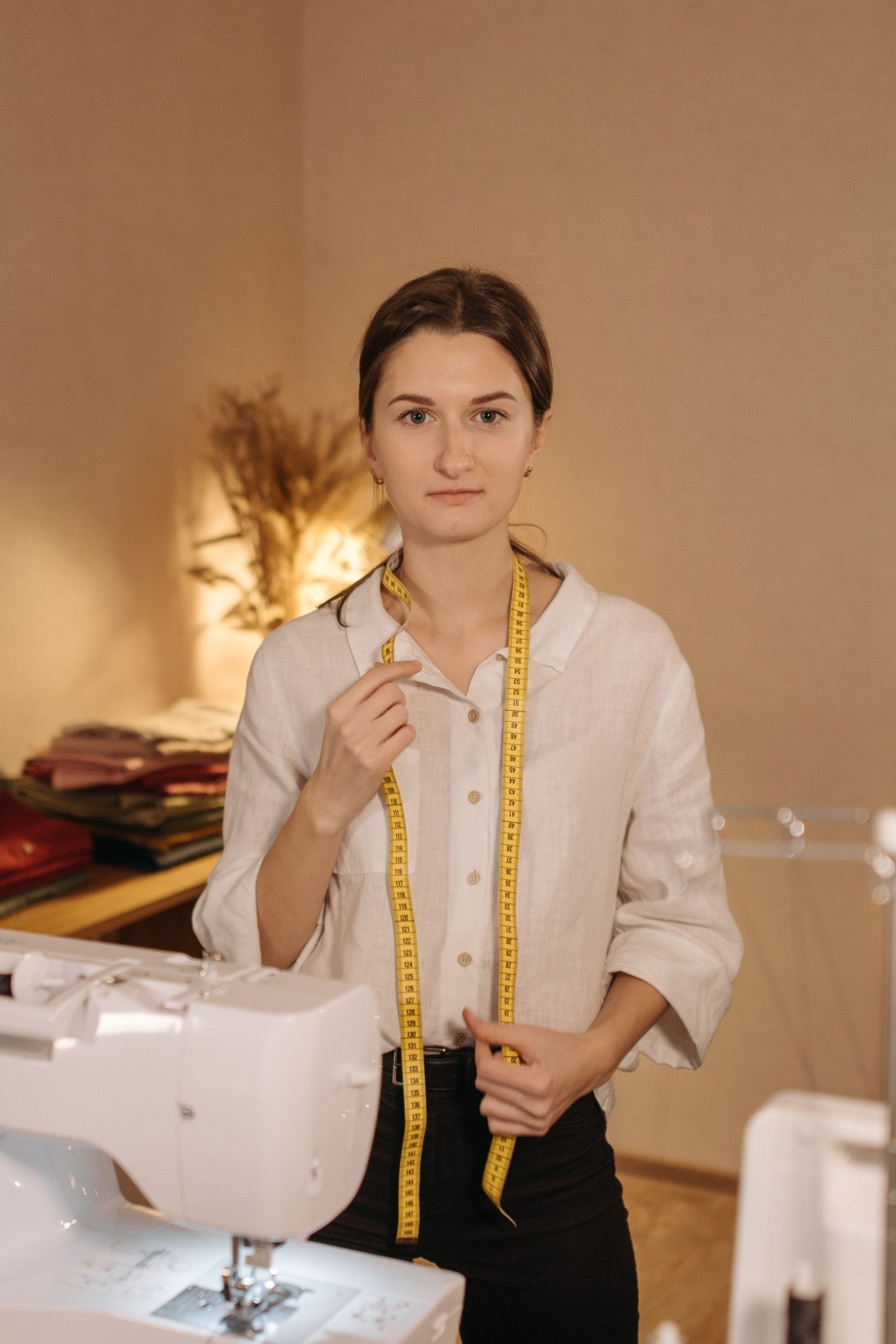 Seamstress with a tape measure around her neck in her studio